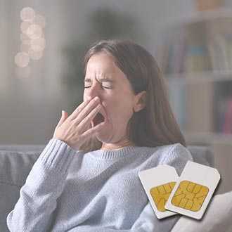 Young woman in light grey jumper sits on couch and yawns with fatigue